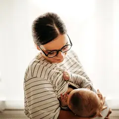 Matka karmi piersią dziecko, które już nie ulewa. Delikatny uścisk, spojrzenie pełne miłości.