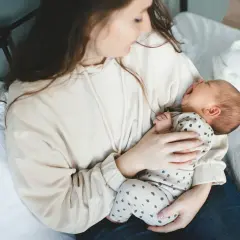Mama tuli do synka, który właśnie zaczął wymioty u niemowlaka. Dziecko z otwartą buzią, mama tuli go czule.