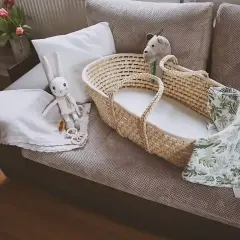 Uroczy koszyk mojżesza z pluszowym zajączkiem i kocykiem w liście, gotowy na przyjęcie maluszka.