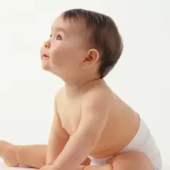 Uroczy 3 miesięczne dziecko podnosi się do siadania, z zaciekawieniem patrząc w górę.