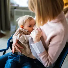 Mama w wózku karmi piersią dziecko. Decyzja o rezygnacji z karmienia piersią może być trudna, ale miłość pozostaje.