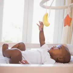 Maluch wyciąga rączkę do bananka na karuzeli do łóżeczka. Od kiedy dziecko zaczyna się nią interesować?
