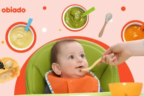 Rozszerzanie diety niemowlaka. Rączka podaje łyżeczkę z jedzeniem ciekawskiemu dziecku w krzesełku. Wokół miseczki z puree.