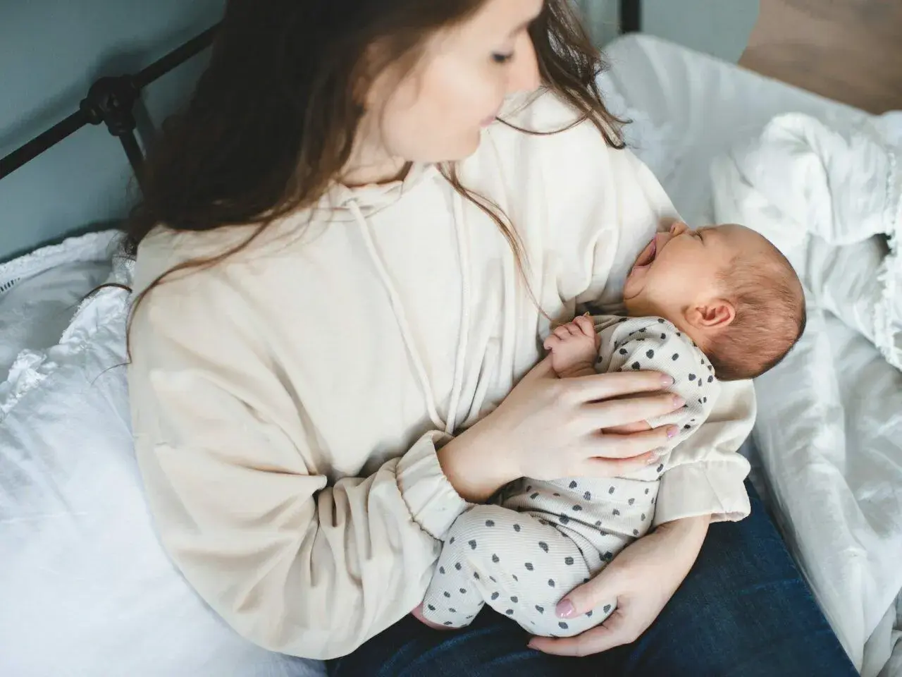 Mama tuli do synka, który właśnie zaczął wymioty u niemowlaka. Dziecko z otwartą buzią, mama tuli go czule.
