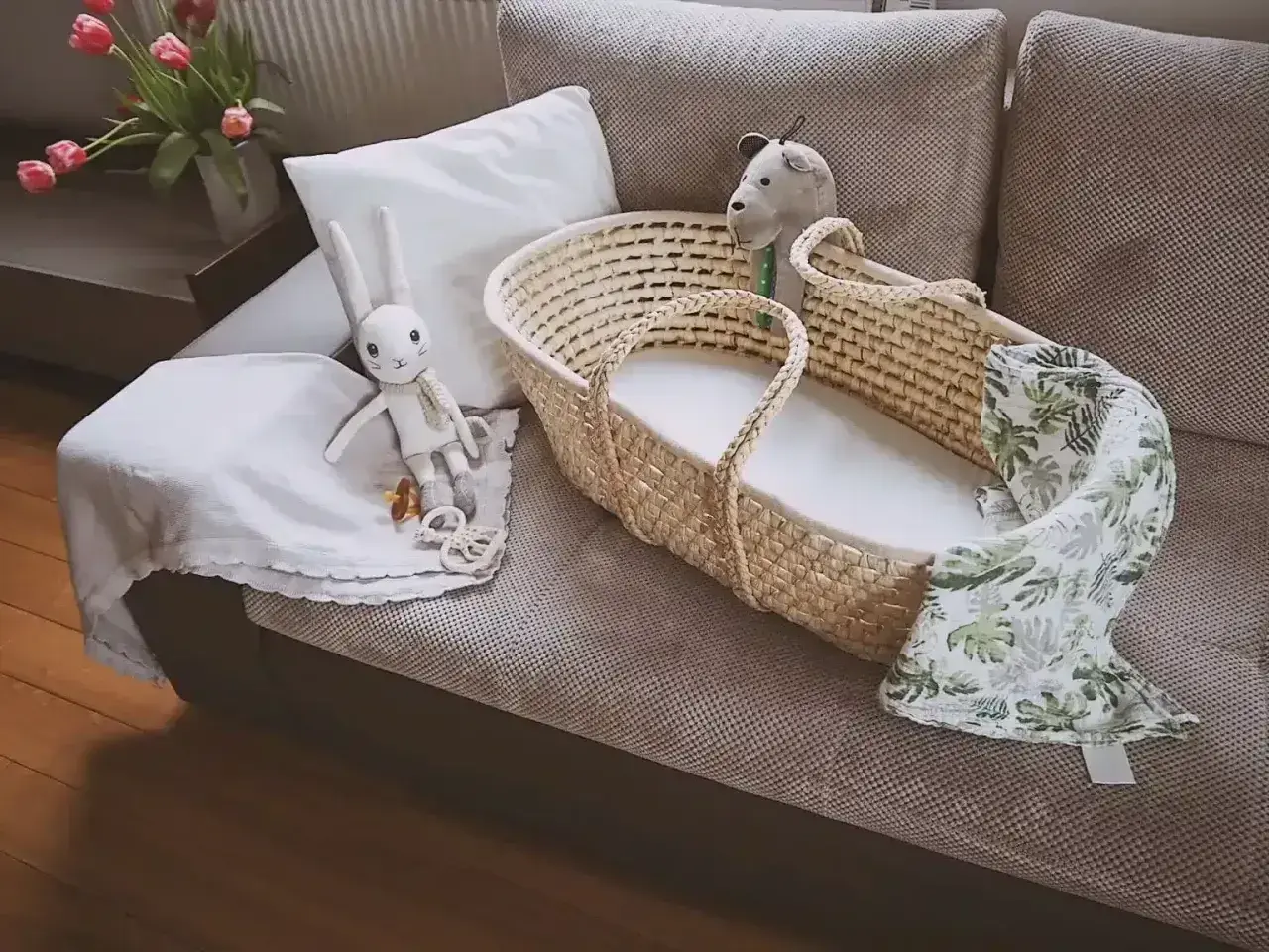 Uroczy koszyk mojżesza z pluszowym zajączkiem i kocykiem w liście, gotowy na przyjęcie maluszka.