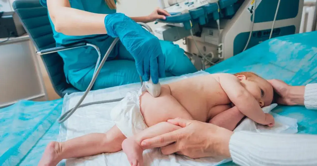 Lekarz wykonuje USG bioderek niemowlaka, sprawdzając, czy nie ma problemów ze strzelającymi stawami.