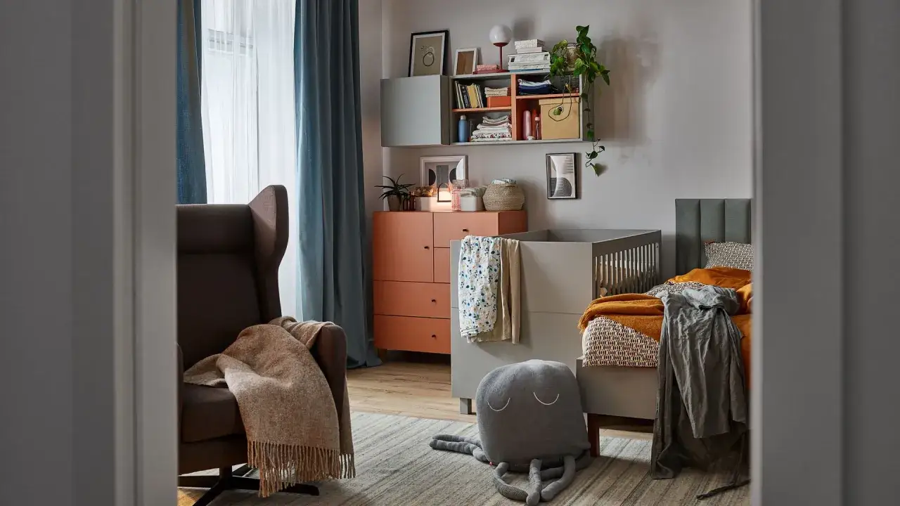 Przytulny kącik do przewijania z fotelem, komodą i łóżeczkiem. Miękkie koce i pluszowa ośmiornica tworzą ciepłą atmosferę.