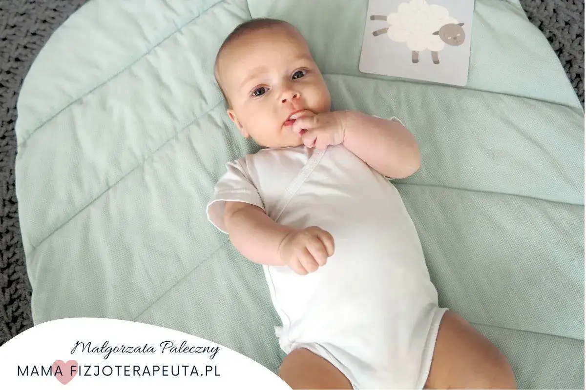 Uroczy 12 tygodniowe dziecko leży na miękkiej macie. W tle karta z owieczką.