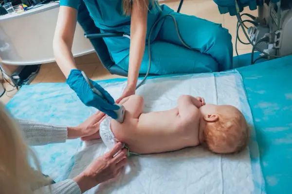 Lekarz wykonuje USG bioderek niemowlaka, sprawdzając, czy nie ma problemów ze strzelającymi stawami.