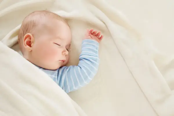 Śpiące dziecko, 22 tydzień życia, otulone w miękki kocyk.